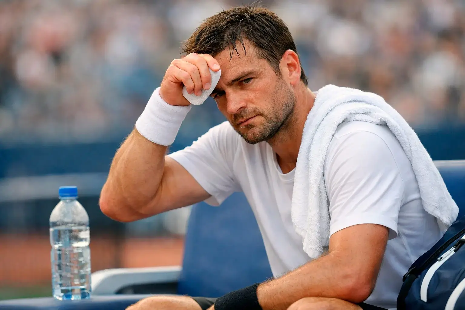Tennisspieler wischt sich Schweiß von der Stirn während einer Pause im Match